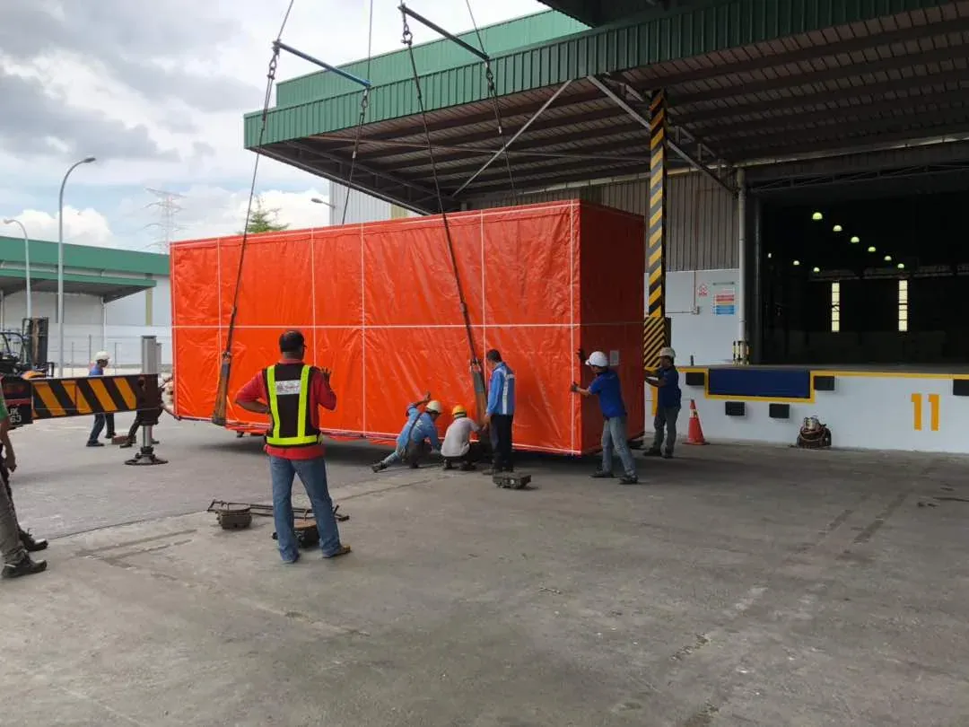 Izaje de equipo protegido con lona frente a bodega industrial