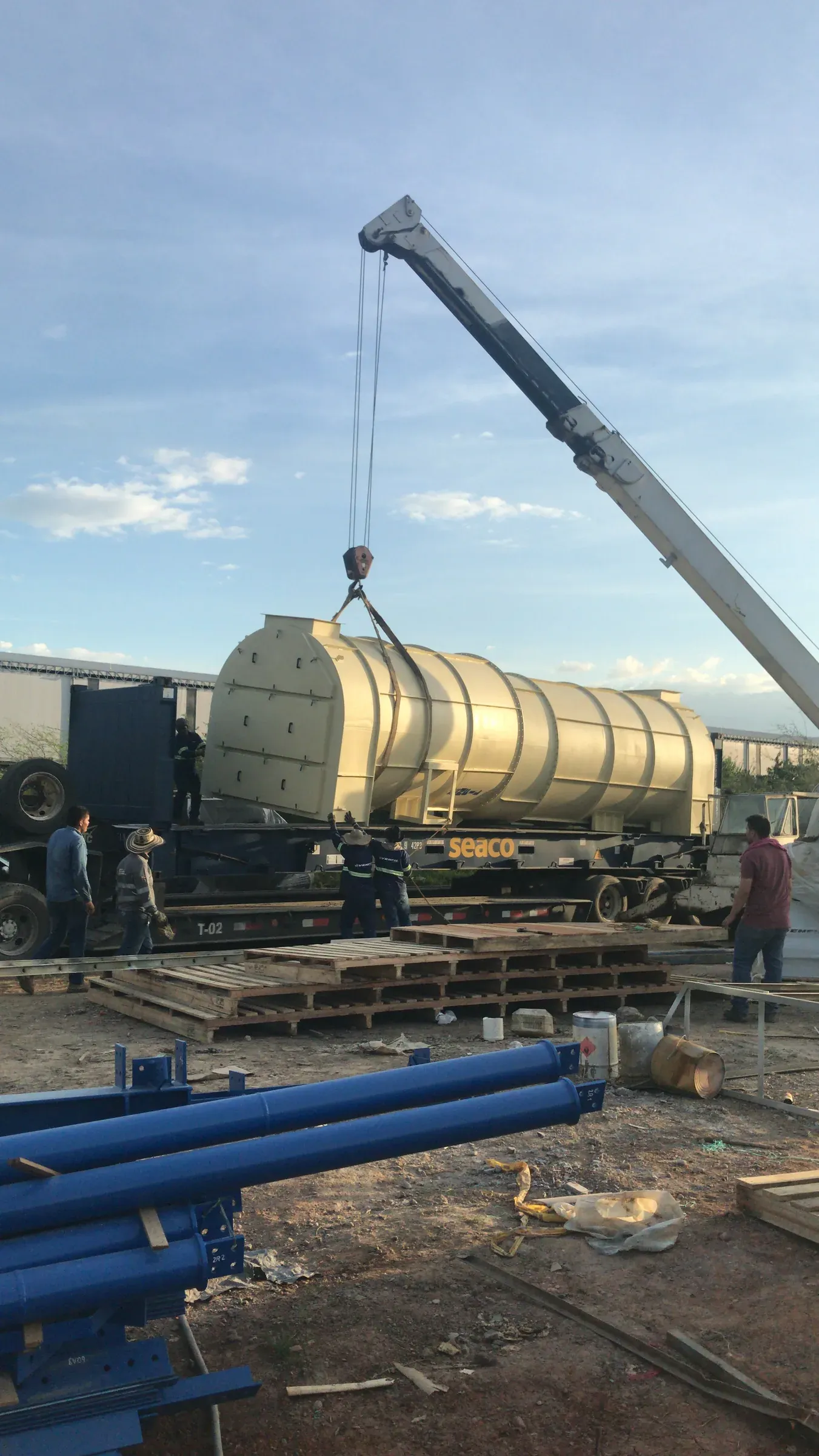 Grúa telescópica izando un tanque industrial en patio de planta