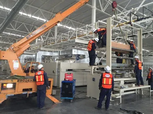 Montaje de equipo con grúa dentro de una nave industrial