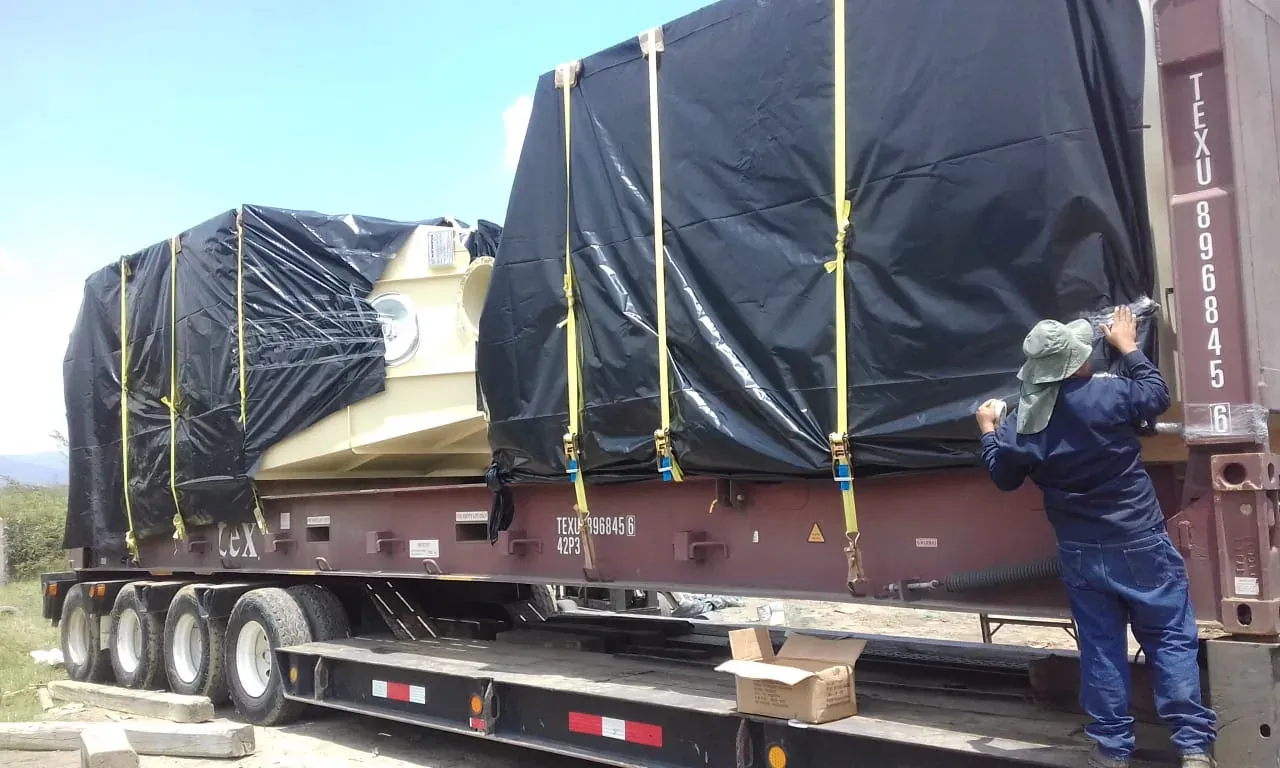 Maquinaria cubierta con lona sobre cama baja para transporte terrestre