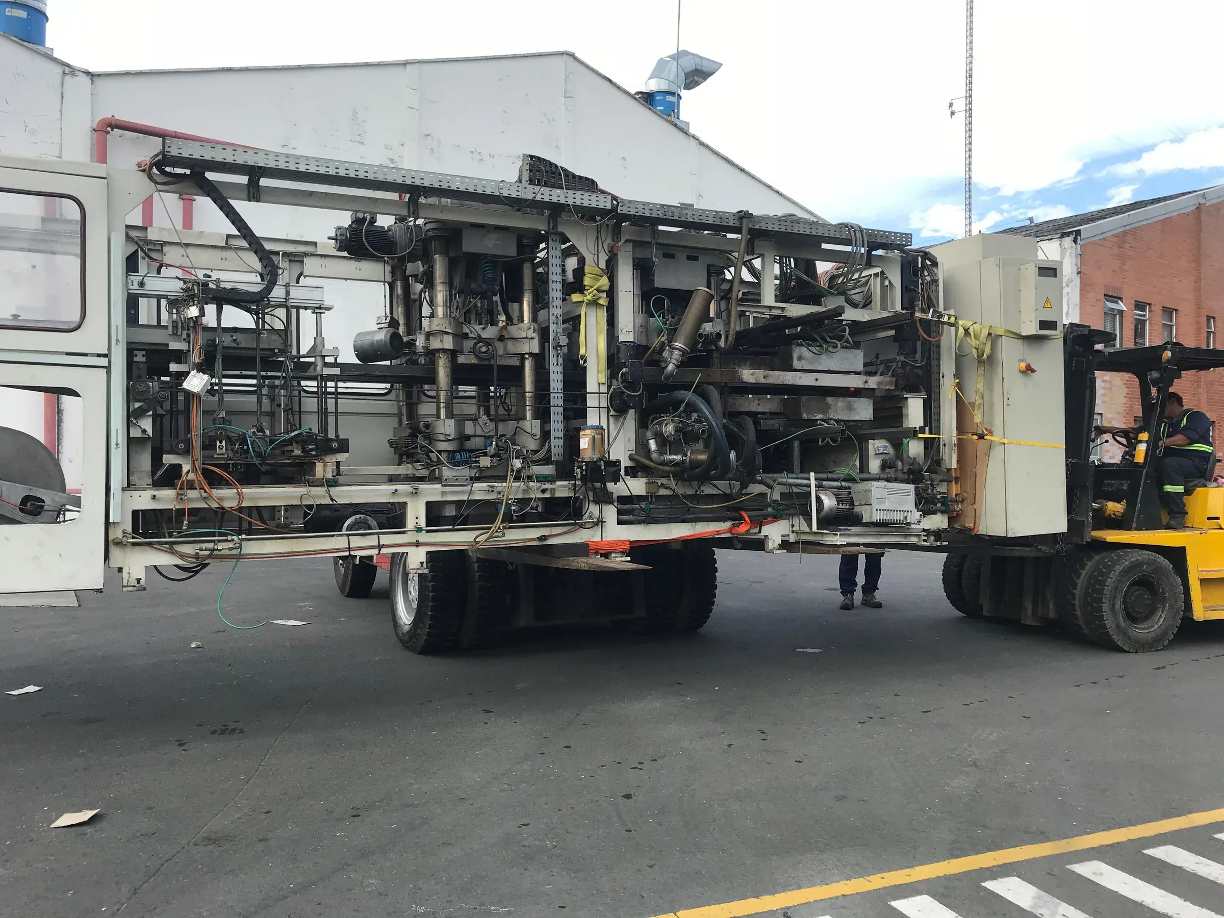 Traslado de máquina industrial sobre vehículo de carga con montacargas
